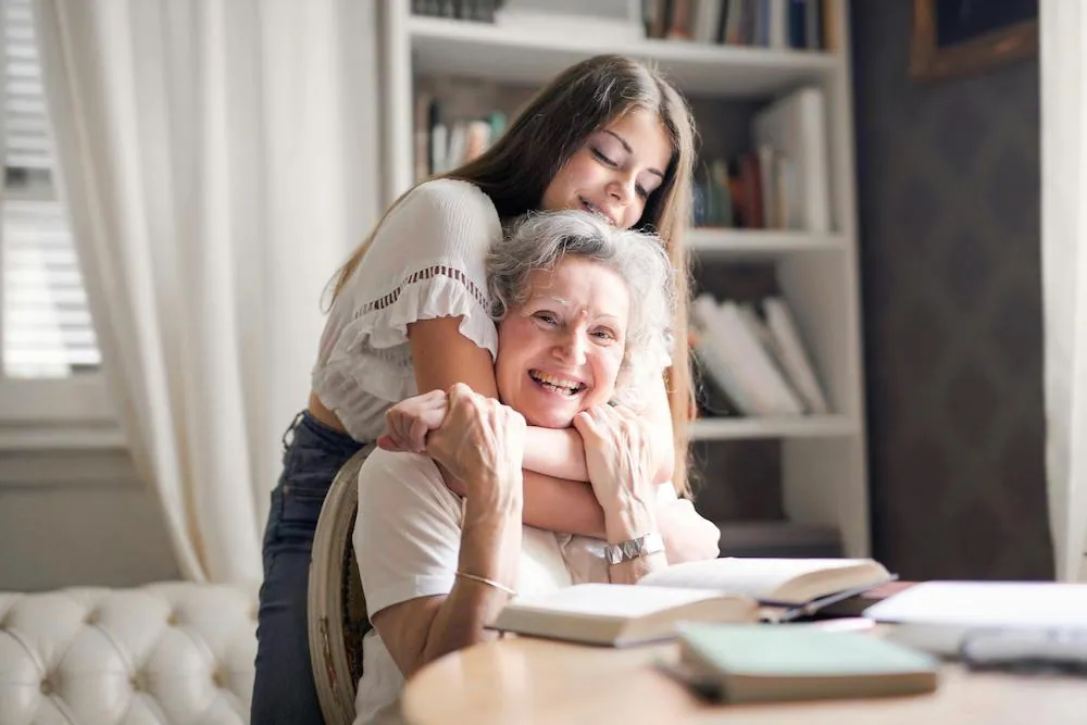 grand daughter hugging smiling grandmother